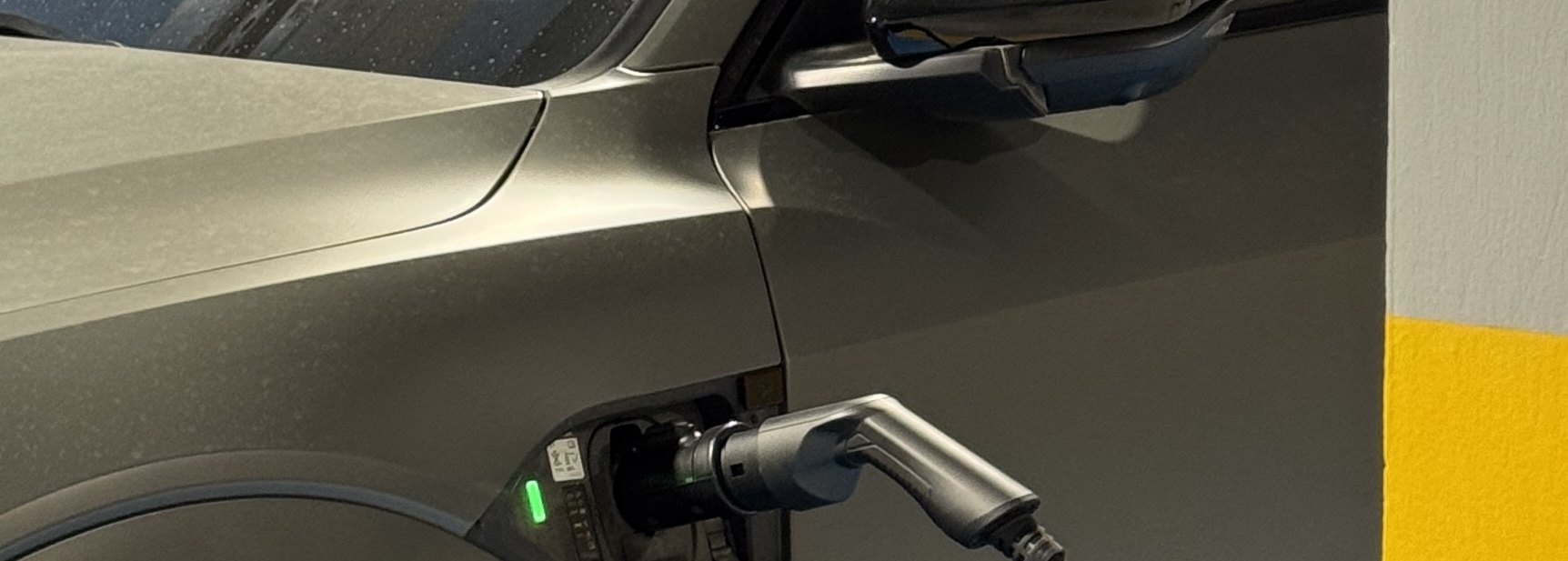 An electric car charging at a wall charger